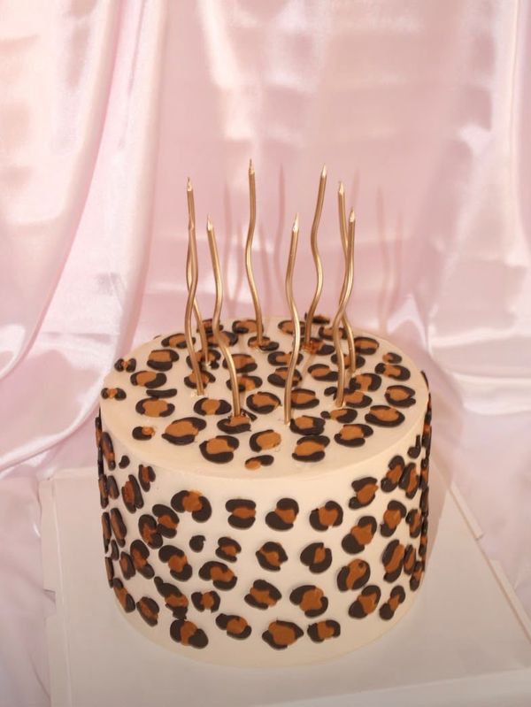 A leopard print cake with tall gold candles