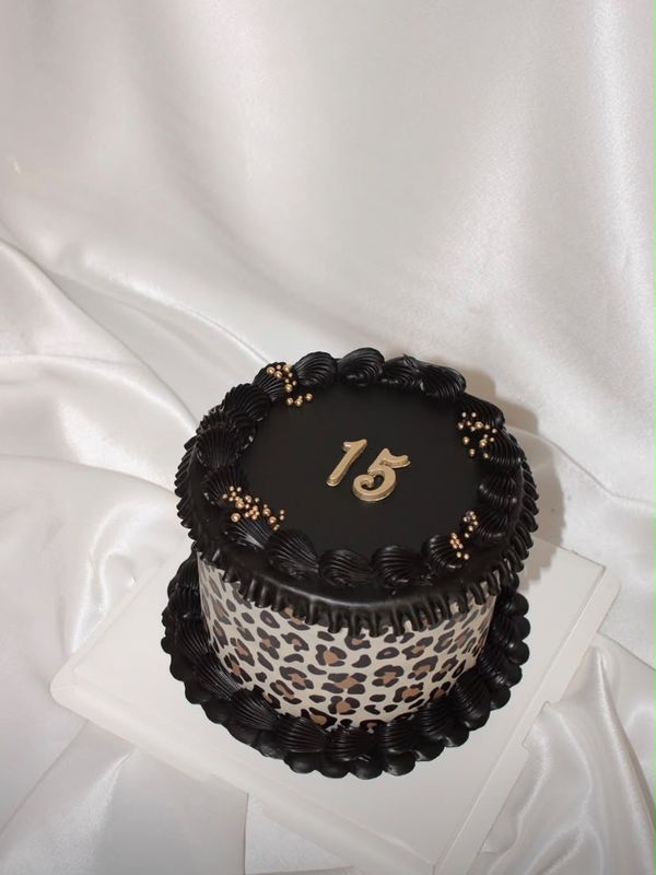 A black and leopard cake topped with a gold 15