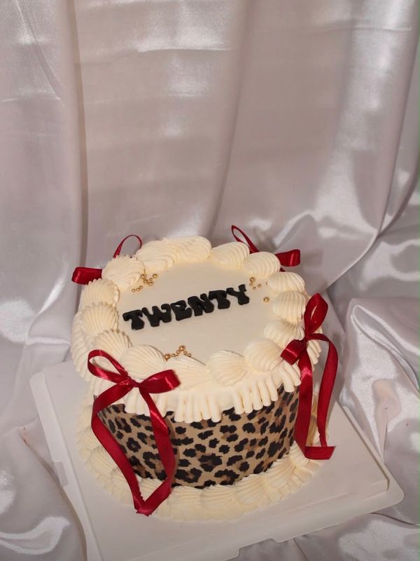 A cream and leopard cake with red bows and TWENTY on top