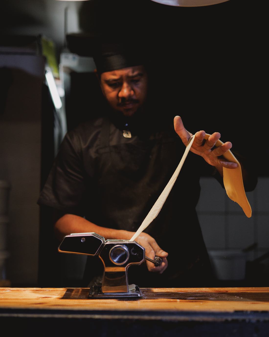 The chef holding up a long sheet of pasta