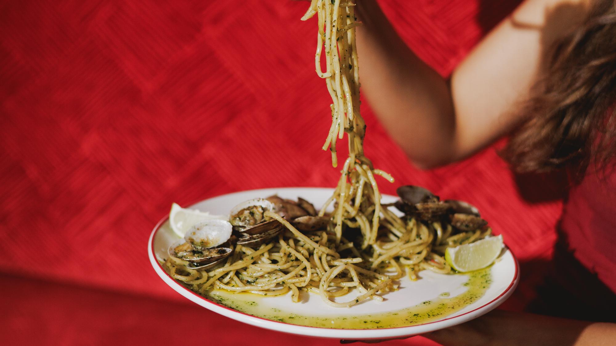 Spaghetti lifted on a fork against red velvet